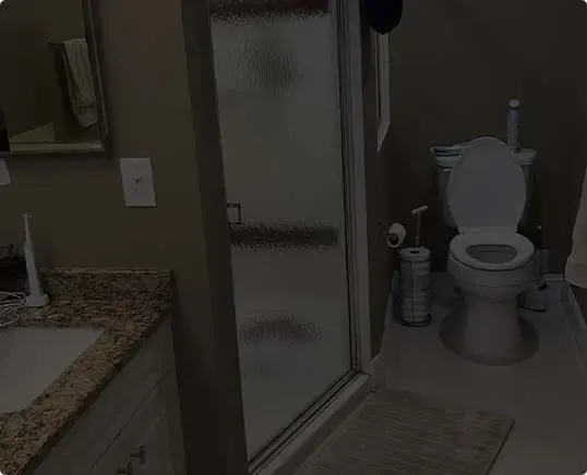 Remodeled bathroom with frosted glass shower door and toilet