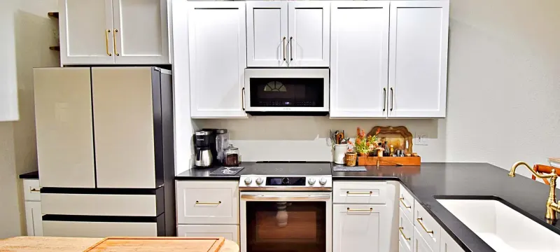 White kitchen with black countertops and brass hardware