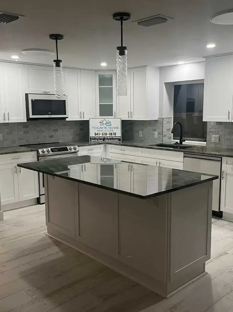 Kitchen island with dark granite top and white cabinets