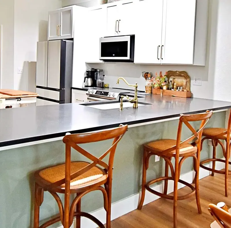 Kitchen island with sage base, gray countertop and wood stools