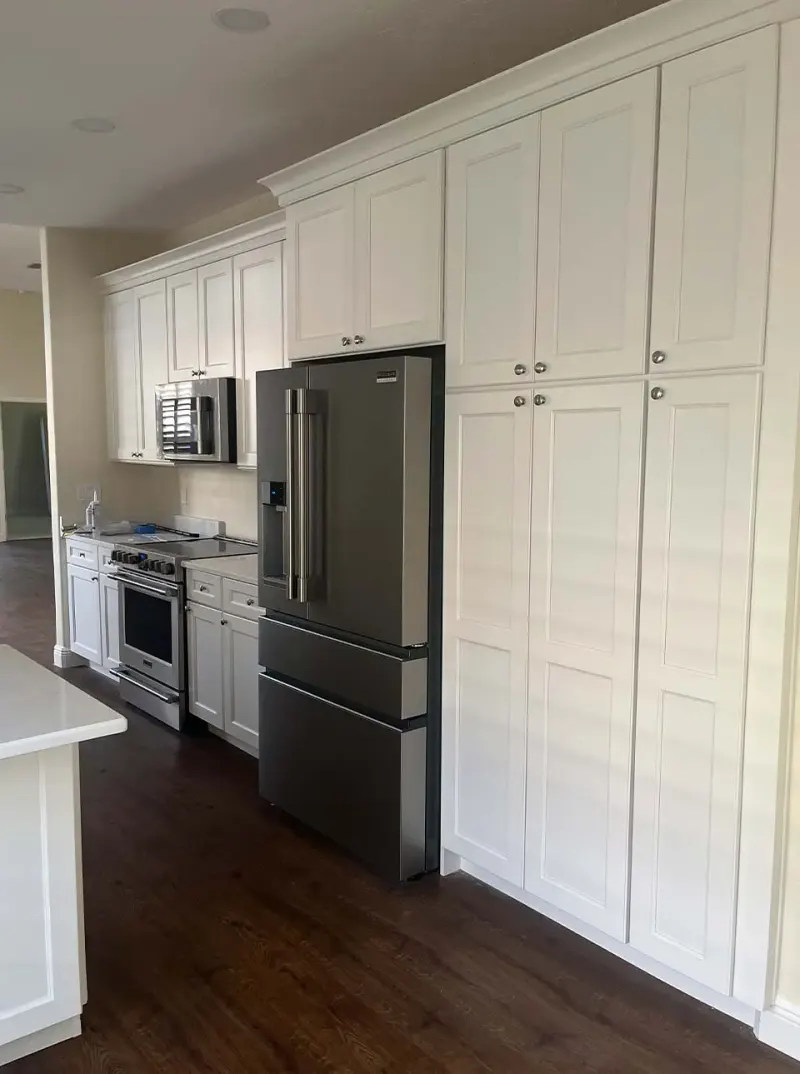 White kitchen with tall cabinets and stainless refrigerator