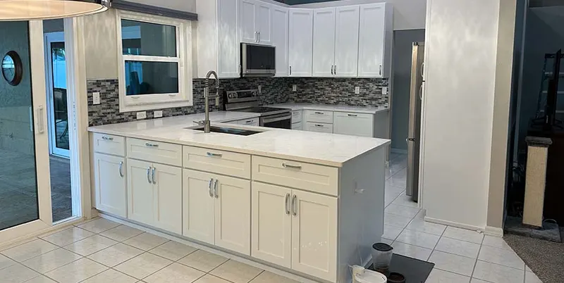 Kitchen remodel with white cabinets, mosaic backsplash and island