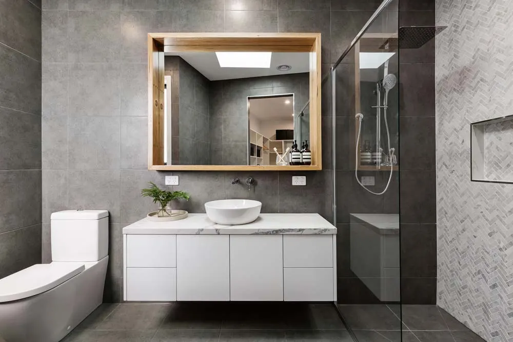 Modern bathroom with floating vanity, framed mirror and herringbone shower tile