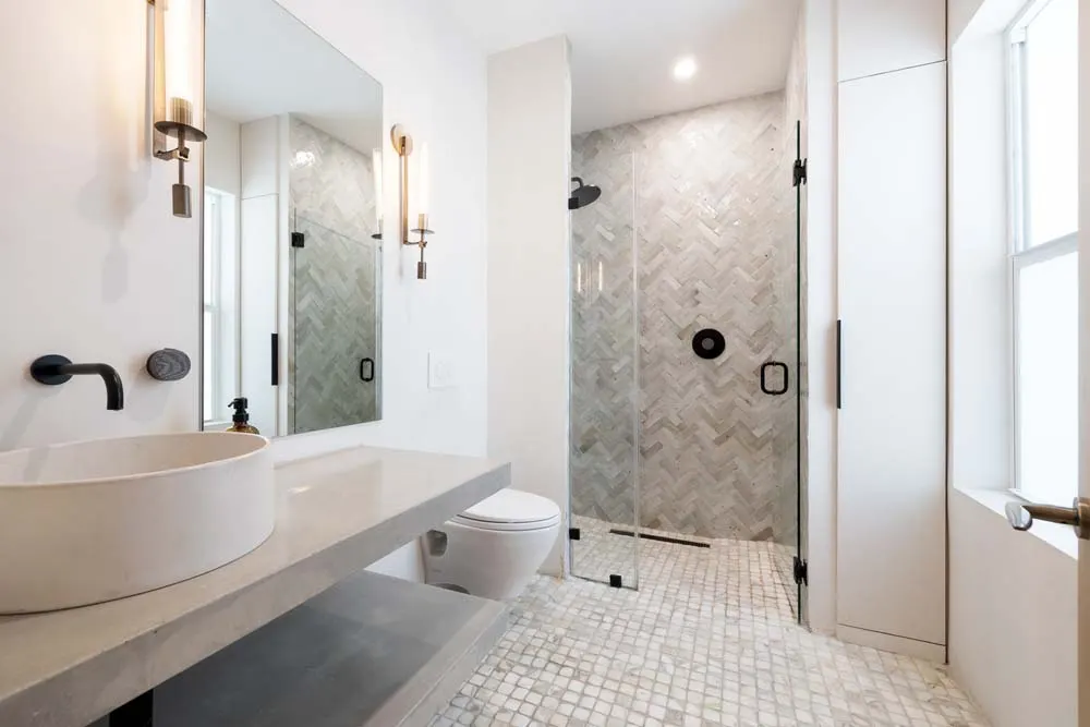 Modern bathroom with vessel sink, walk-in shower and herringbone tile