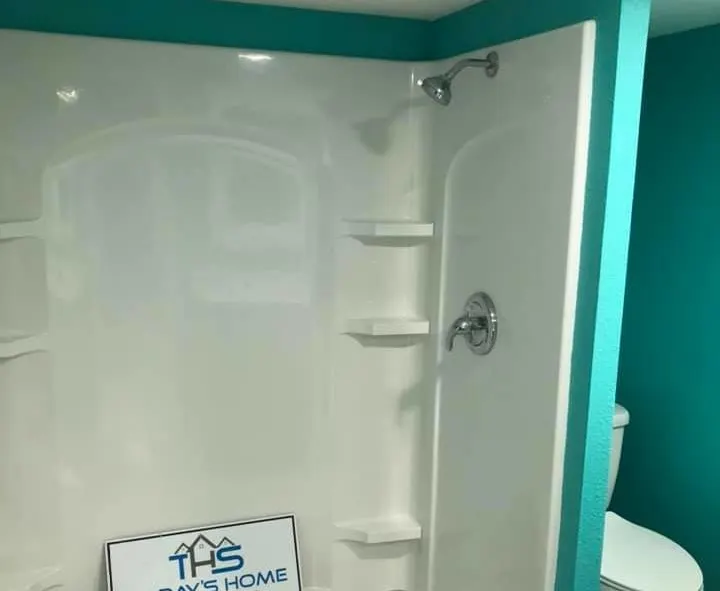White shower surround with glass door and company sign
