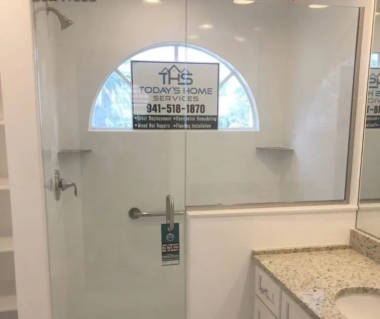 White tile shower with clear glass enclosure beside a granite vanity